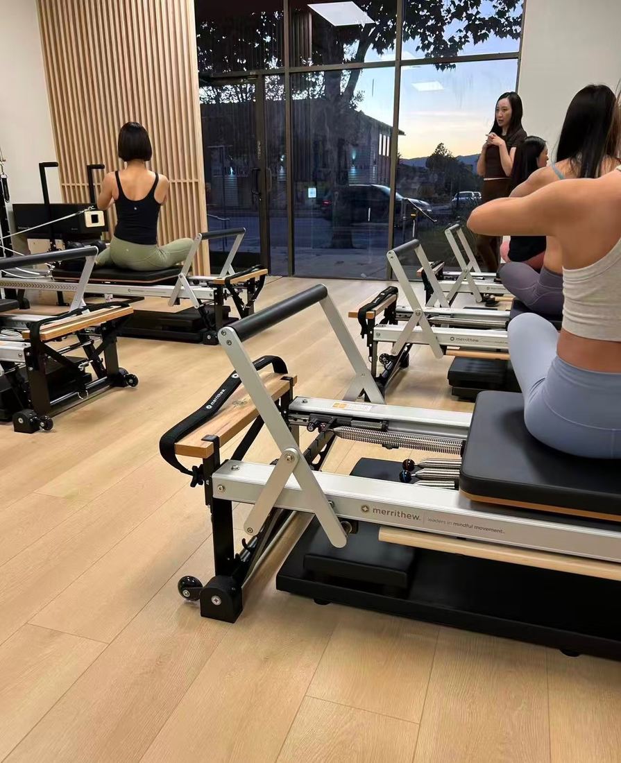 A class on the merrithew reformers in the Aloe Pilates main studio, with evening light through the front windows